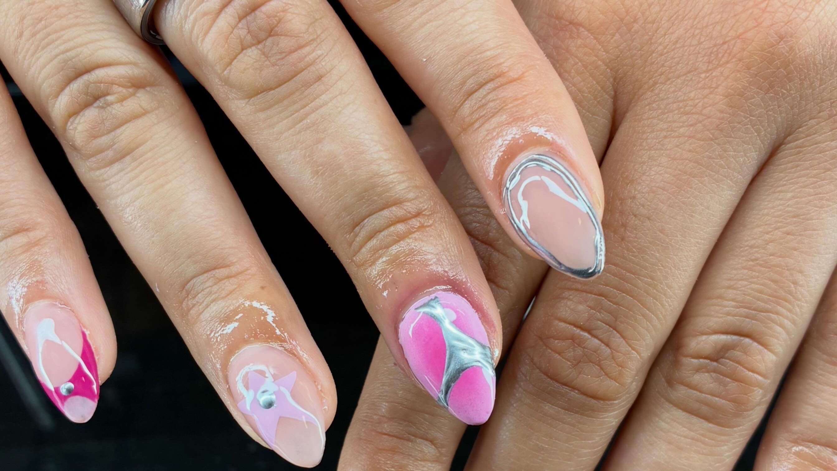 A finished nail set from the salon — almond-shaped nails in nude and pink with silver detailing